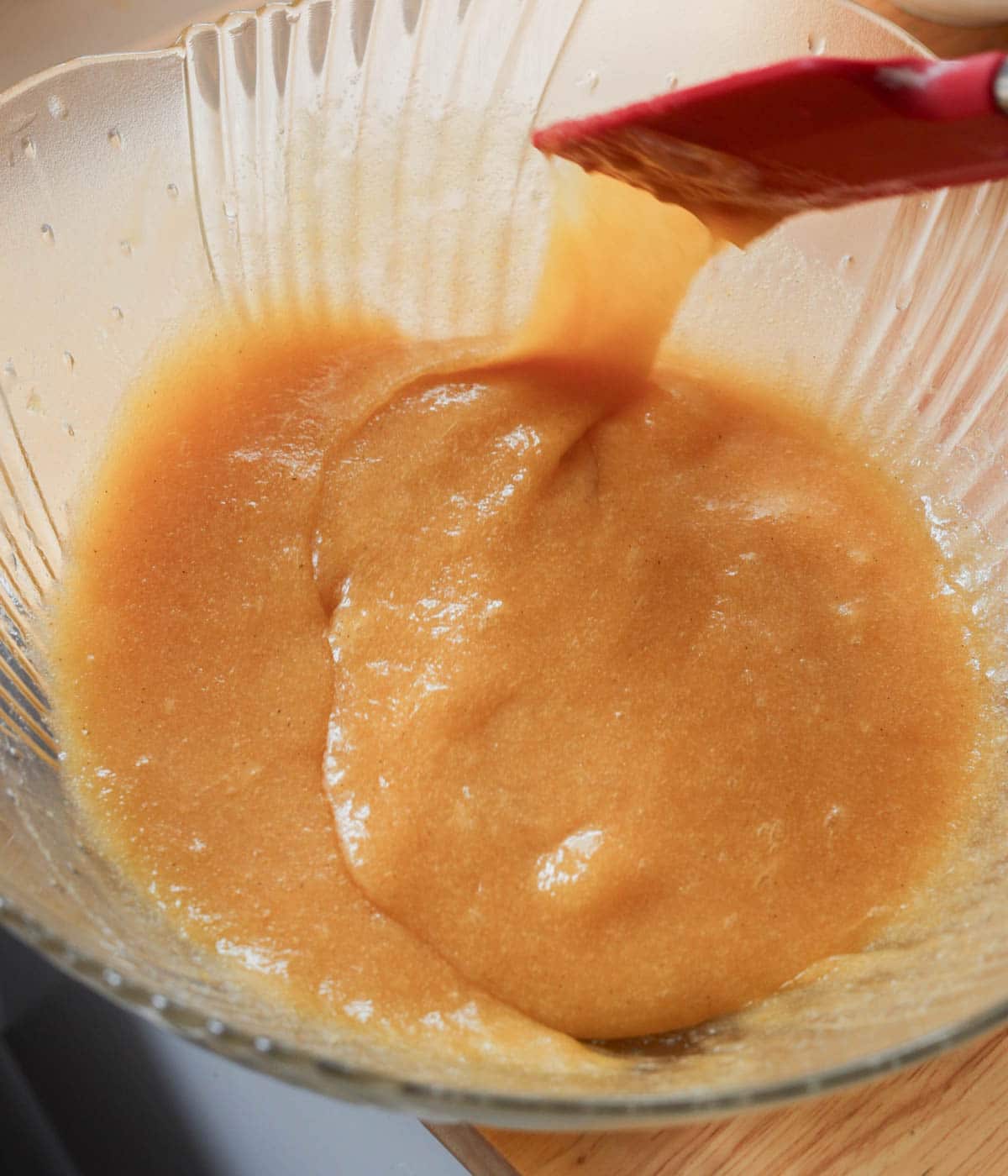 Egg and vanilla mixed in with butter and sugars in a glass bowl.