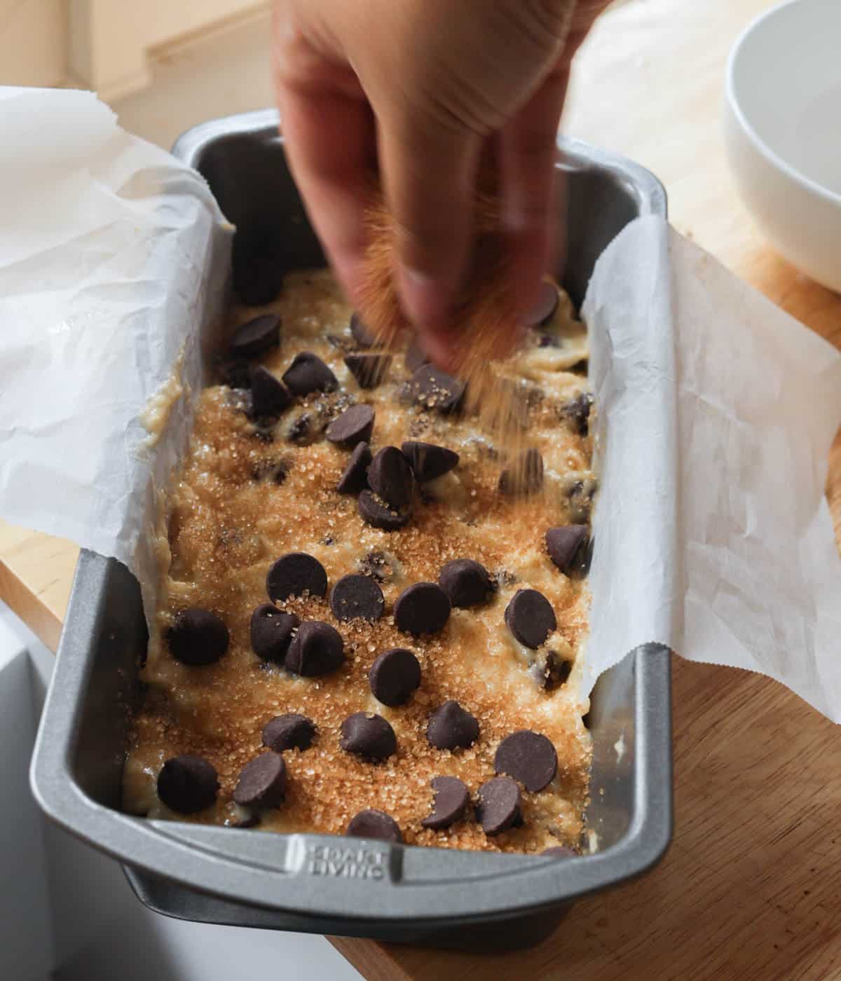 Topping chocolate banana bread batter with more chocolate chips and turbinado sugar.