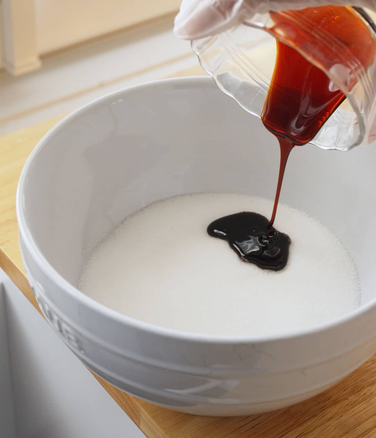 Pouring molasses into mixing bowl with sugar.