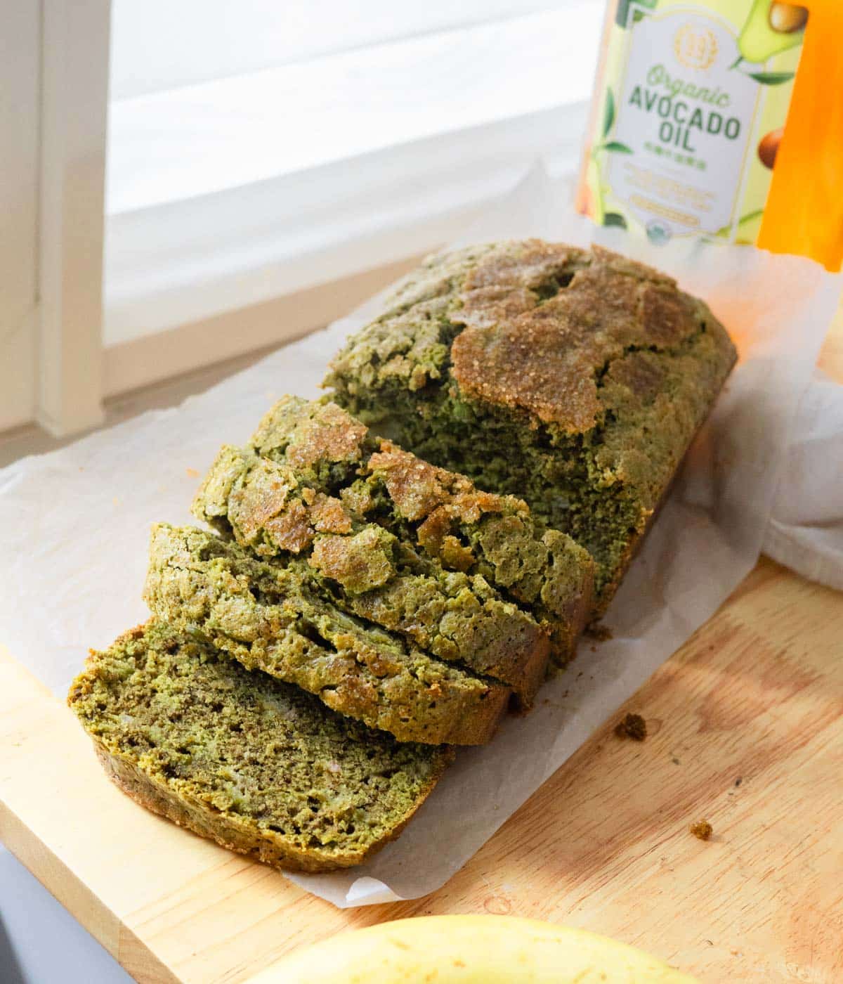 Green matcha banana bread with half of it cut into slices.