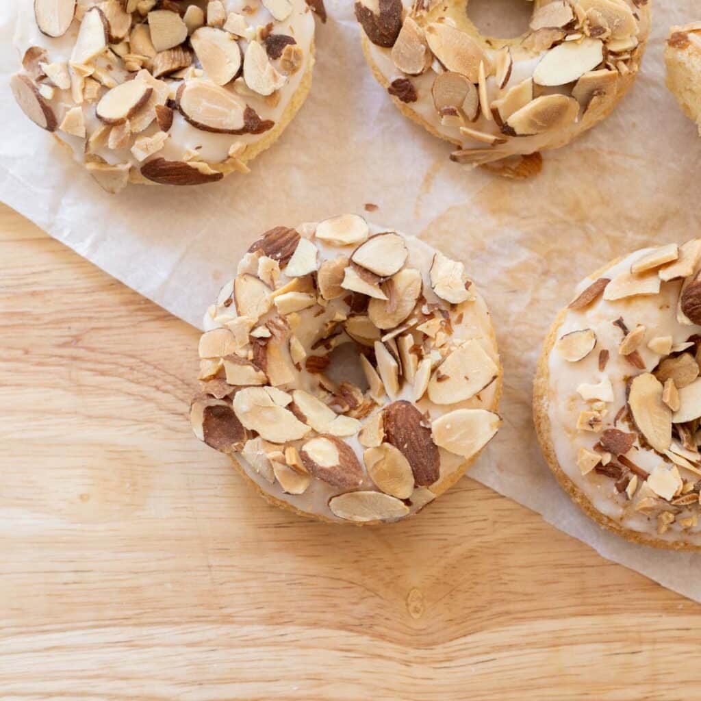 Almond mochi donuts on wooden table lined with parchment paper.