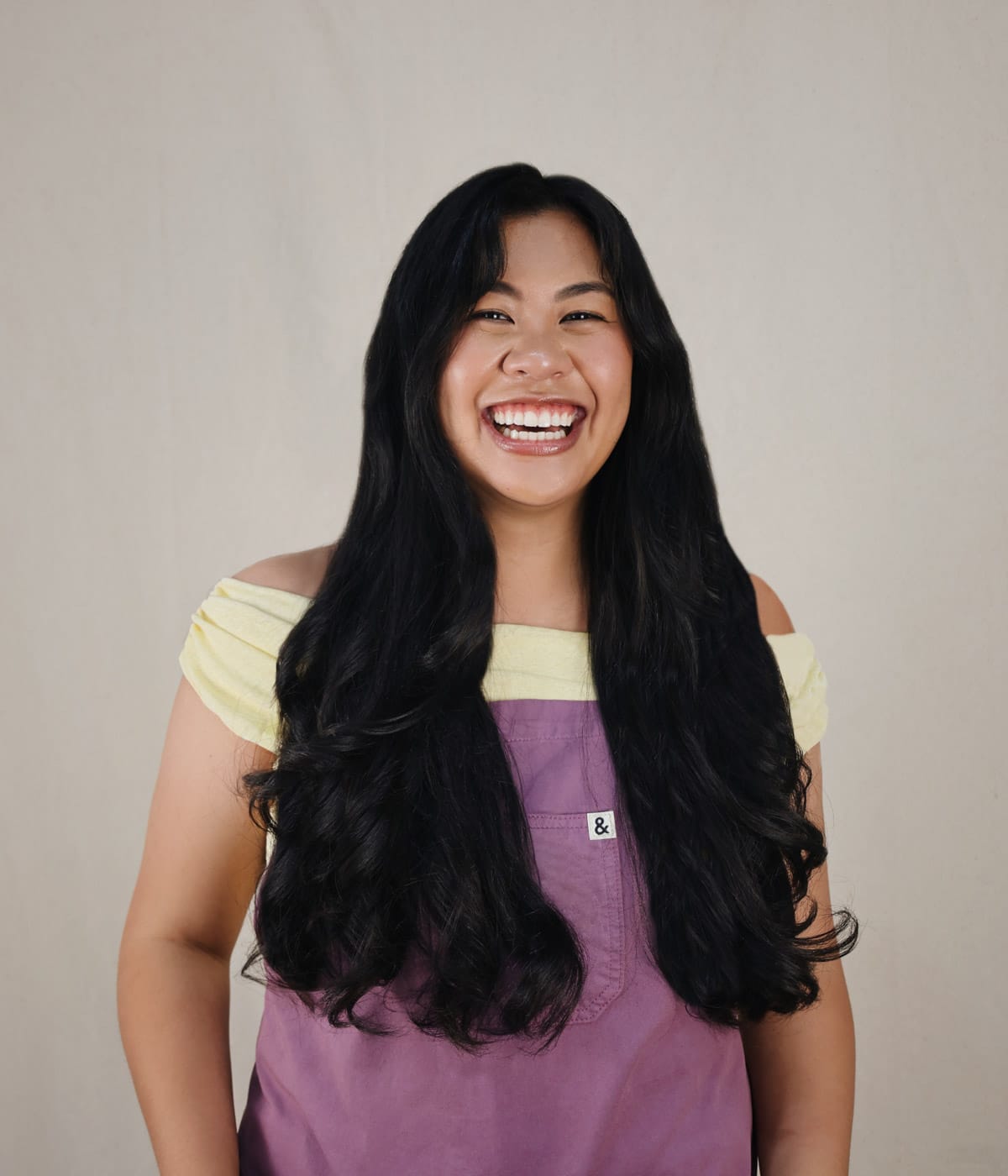 Bites by Bianca smiling at camera wearing purple apron and yellow top.