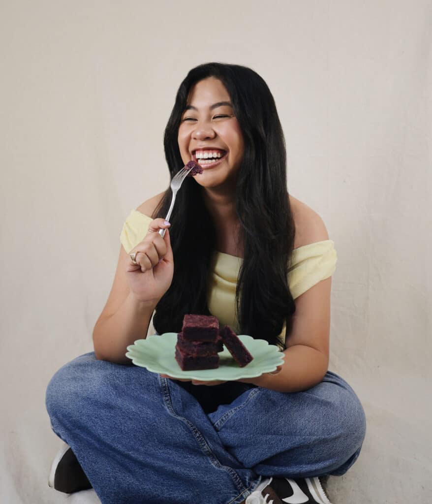 Bites by Bianca taking bite of Oh So Easy Ube Blondies with a fork.