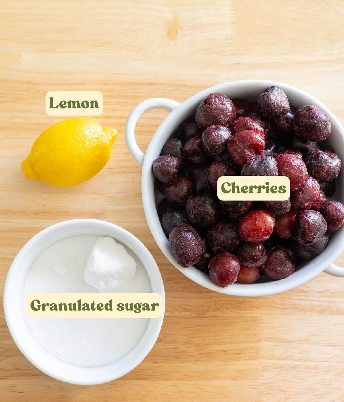 Cherry jam labeled ingredients laid out on a wooden table.