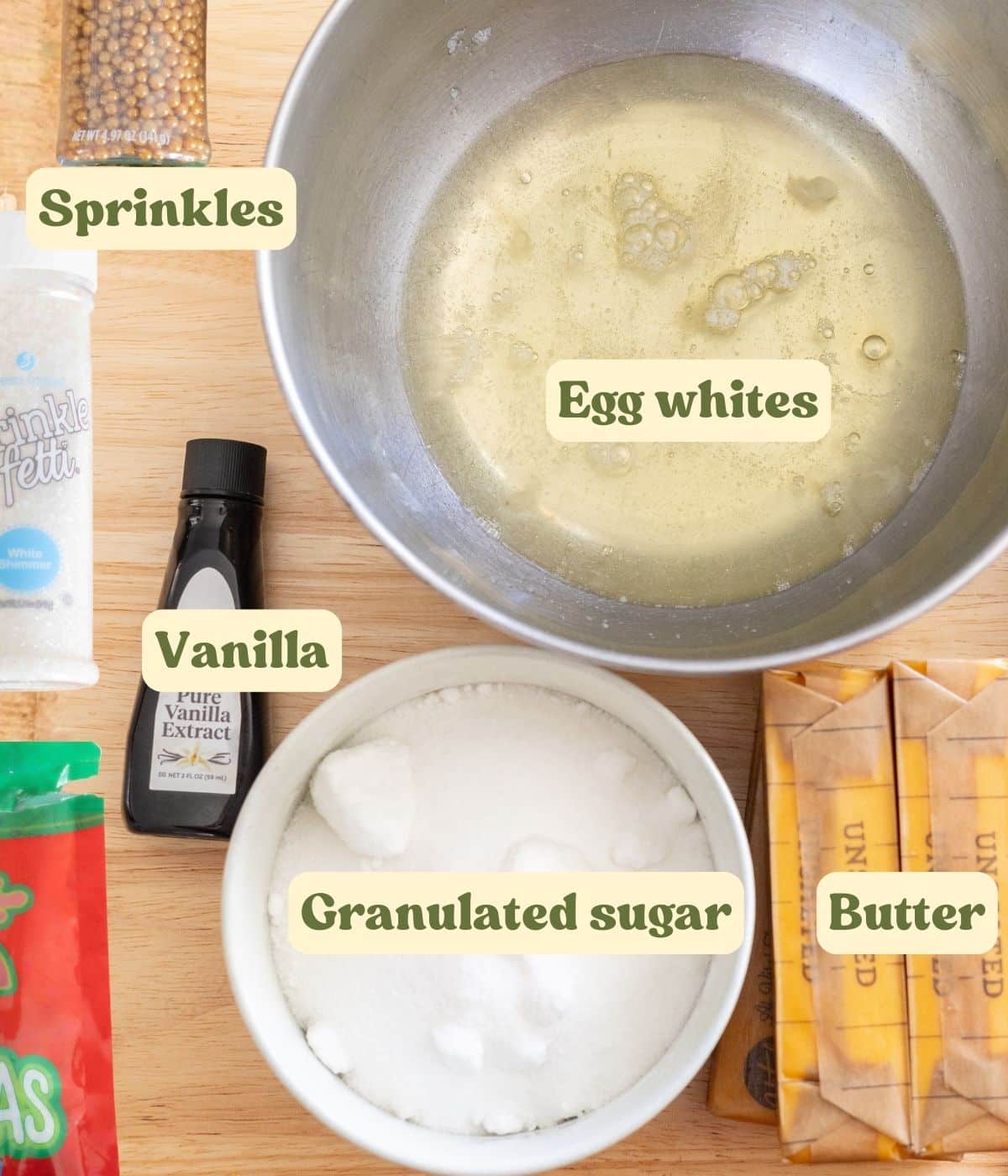 Christmas tree cake frosting and decoration labeled ingredients laid out on a wooden table.