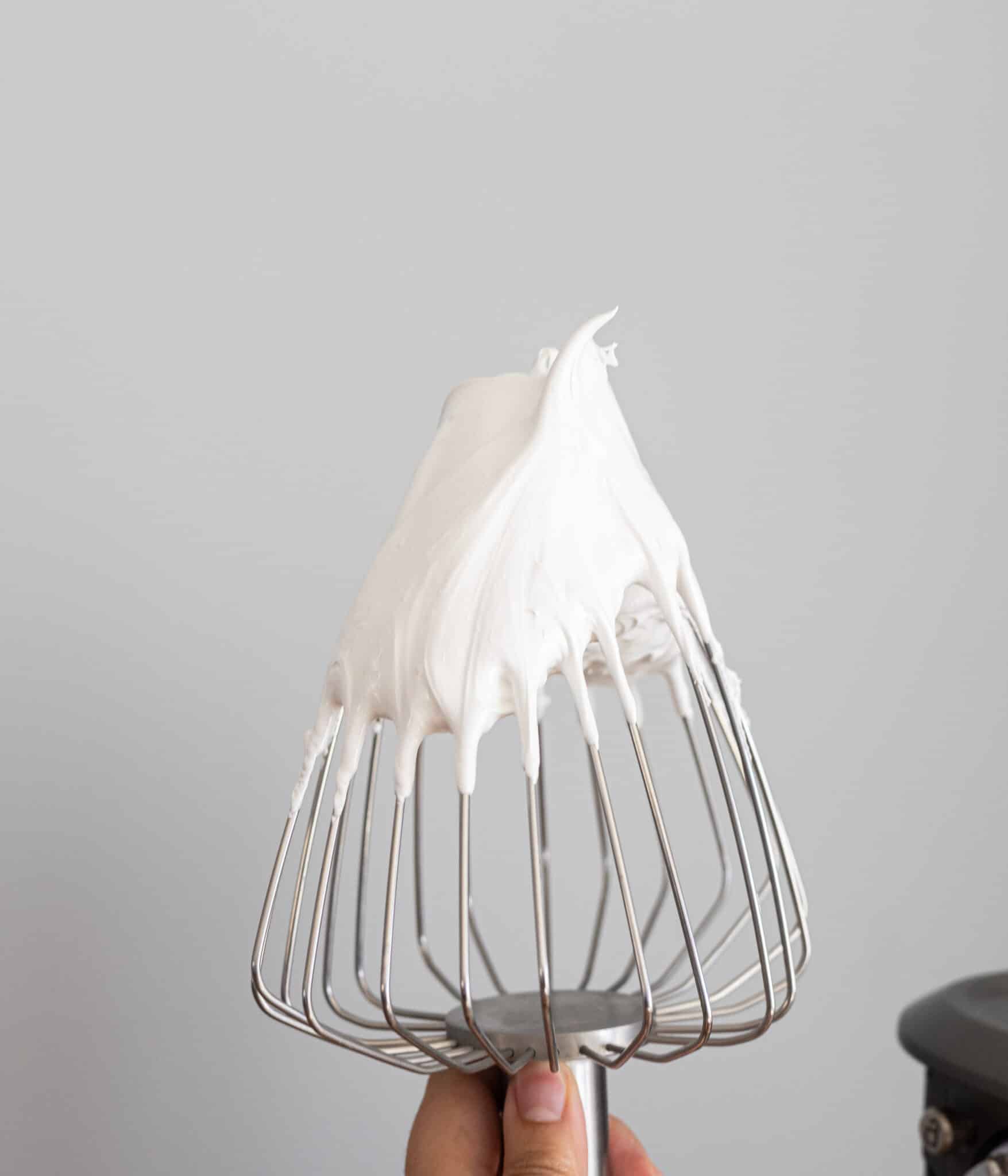 Flfufy swiss meringue with stiff peaks on a balloon whisk.