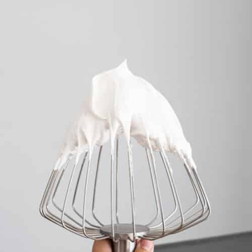 Flfufy swiss meringue with stiff peaks on a balloon whisk.