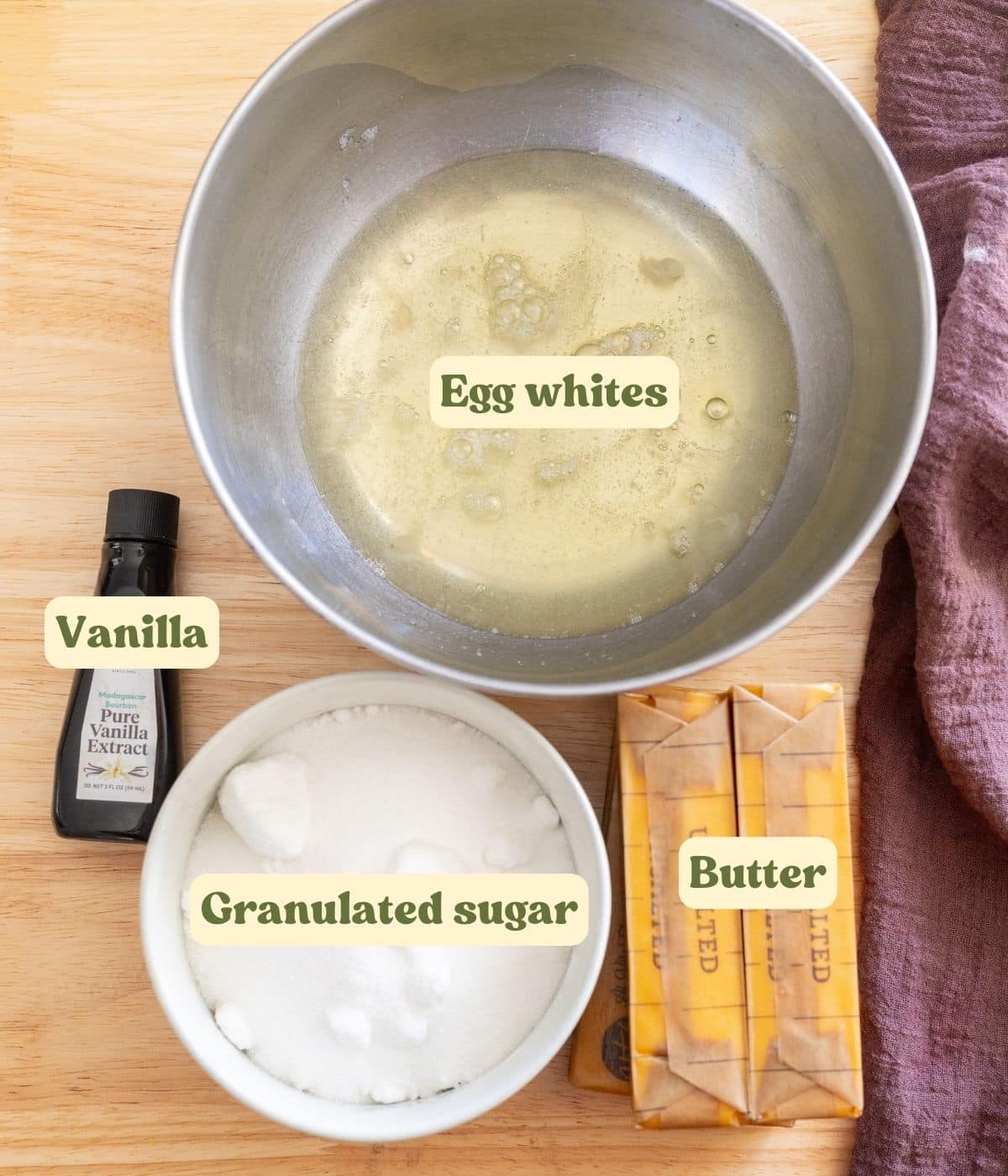 Swiss meringue buttercream labeled ingredients laid out on a wooden table.