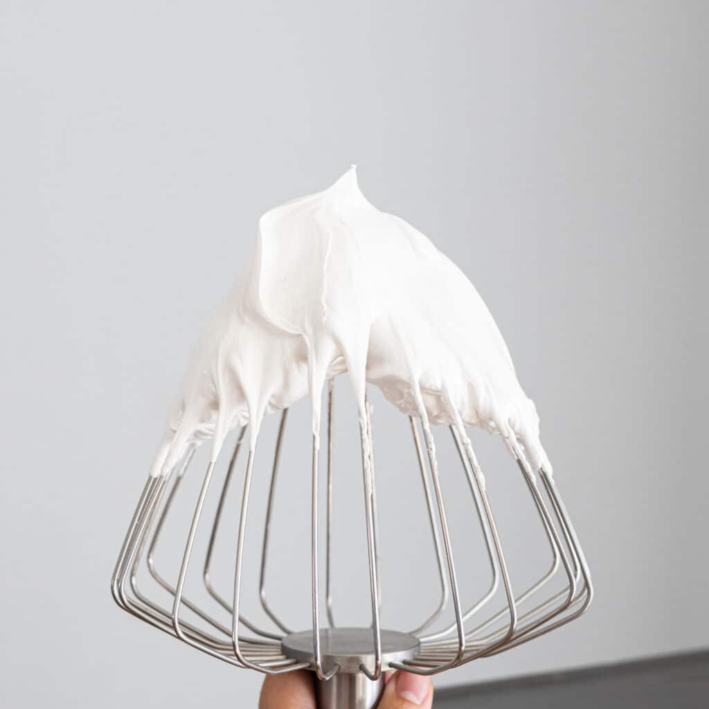 Flfufy swiss meringue with stiff peaks on a balloon whisk.