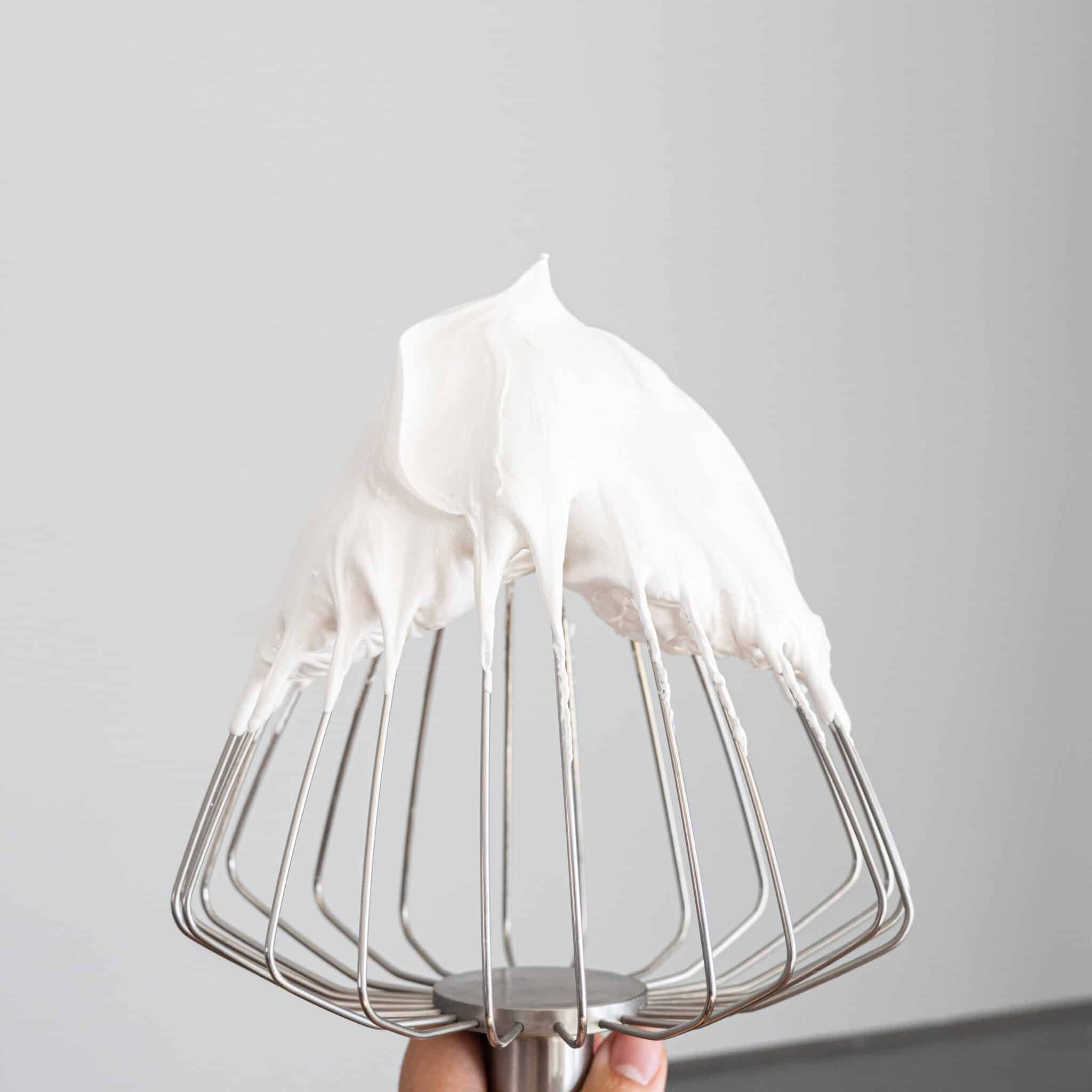 Flfufy swiss meringue with stiff peaks on a balloon whisk.