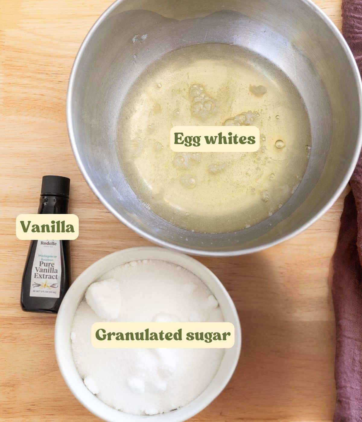 Swiss meringue labeled ingredients laid out on a wooden table.