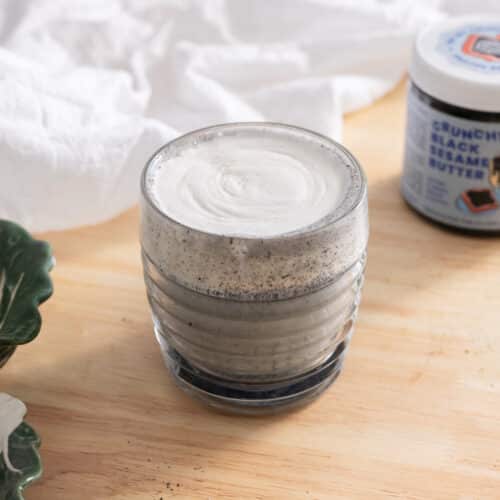 Black sesame latte topped with cheese foam in a glass cup.