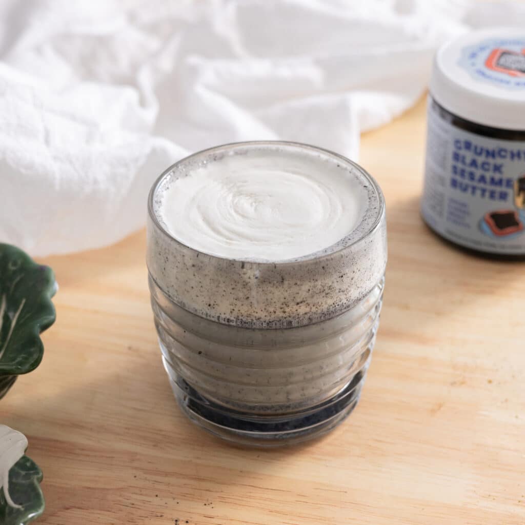 Black sesame latte topped with cheese foam in a glass cup.