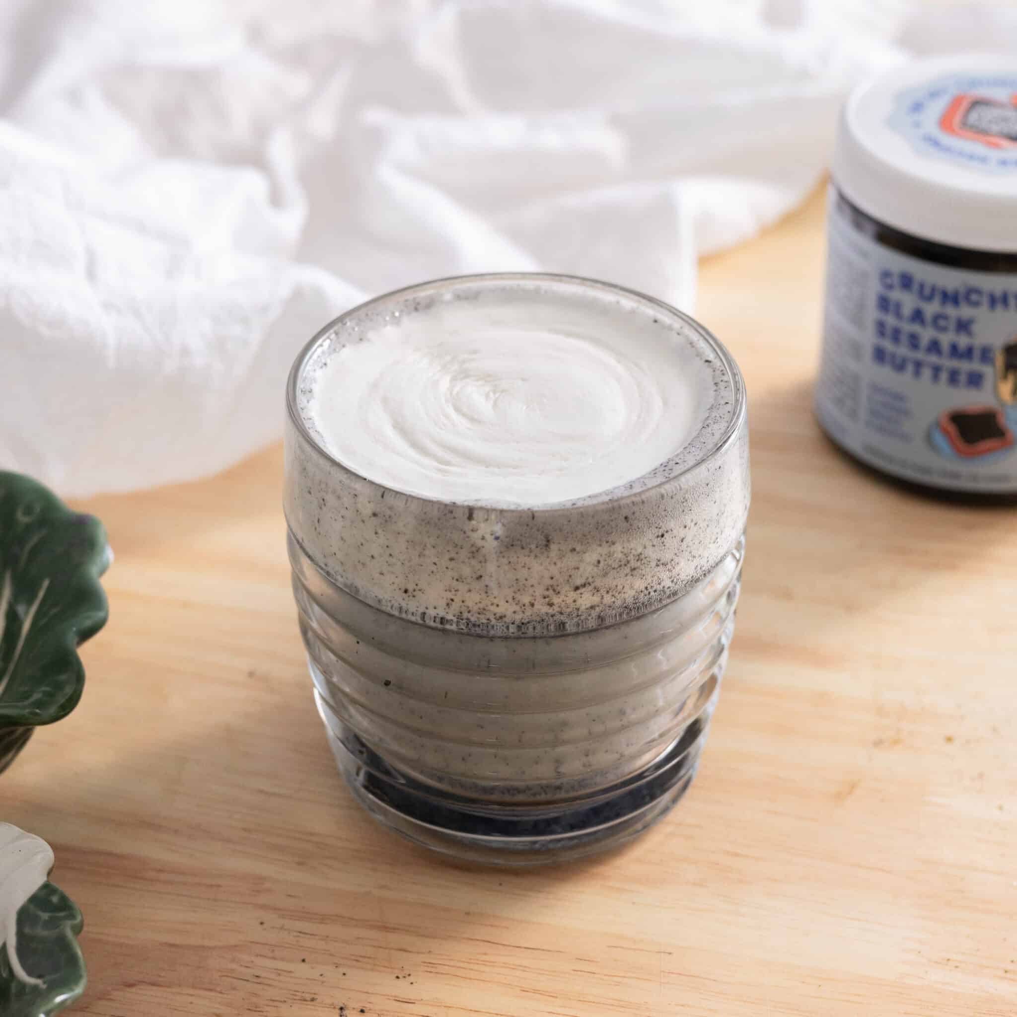 Black sesame latte topped with cheese foam in a glass cup.