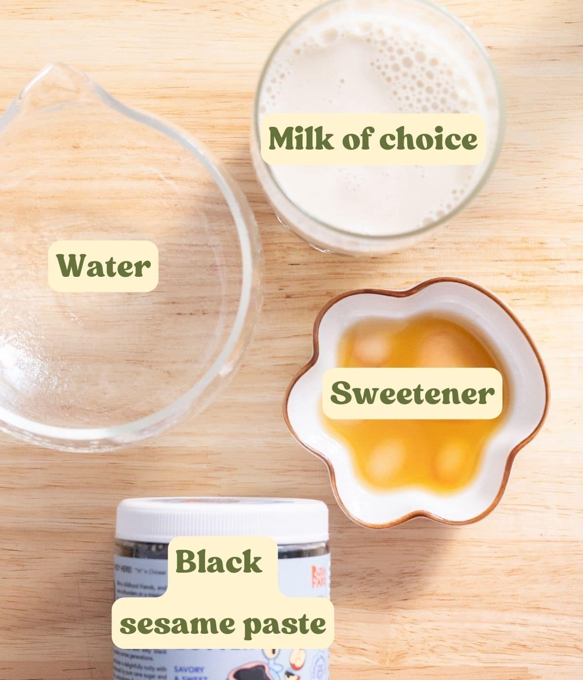Black sesame latte labeled ingredients laid out on a wooden table.