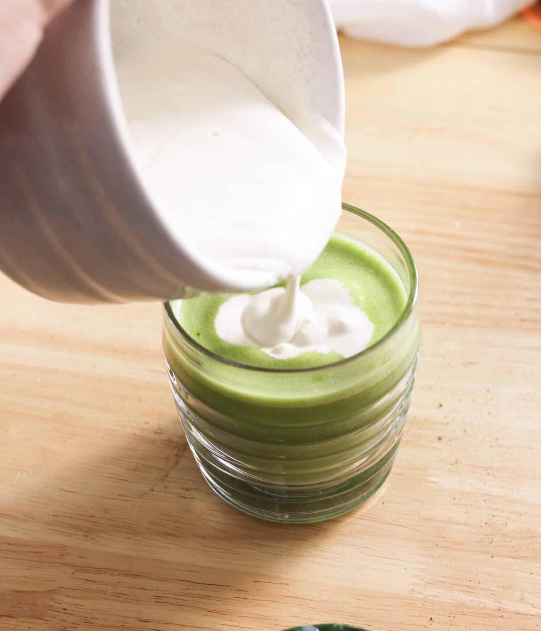 Pouring brown sugar cold foam over matcha latte.