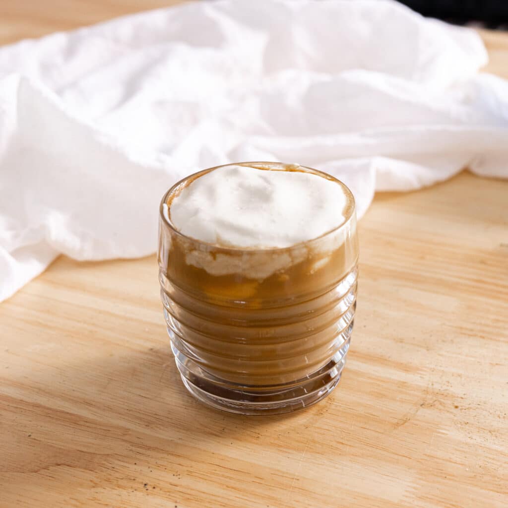Latte topped with cheese cold foam in a glass mug.
