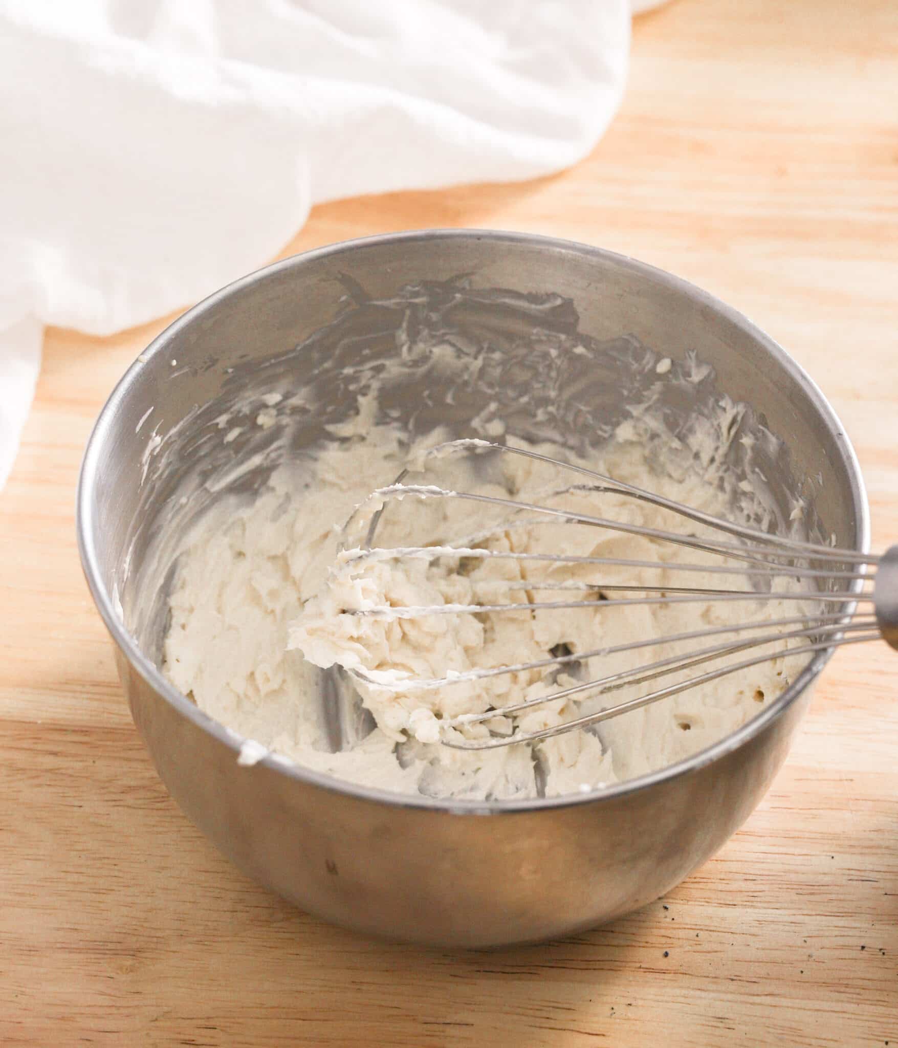 Softened cream cheese and sweetener mixed together in a stainless steel bowl.