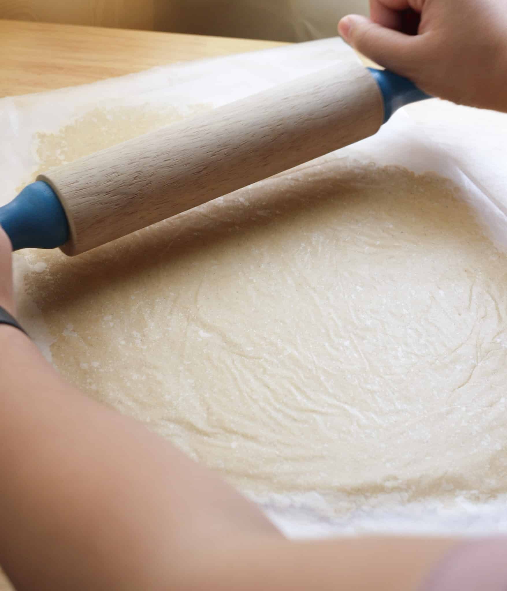Rolling out sugar cookie dough between to pieces of wax paper.