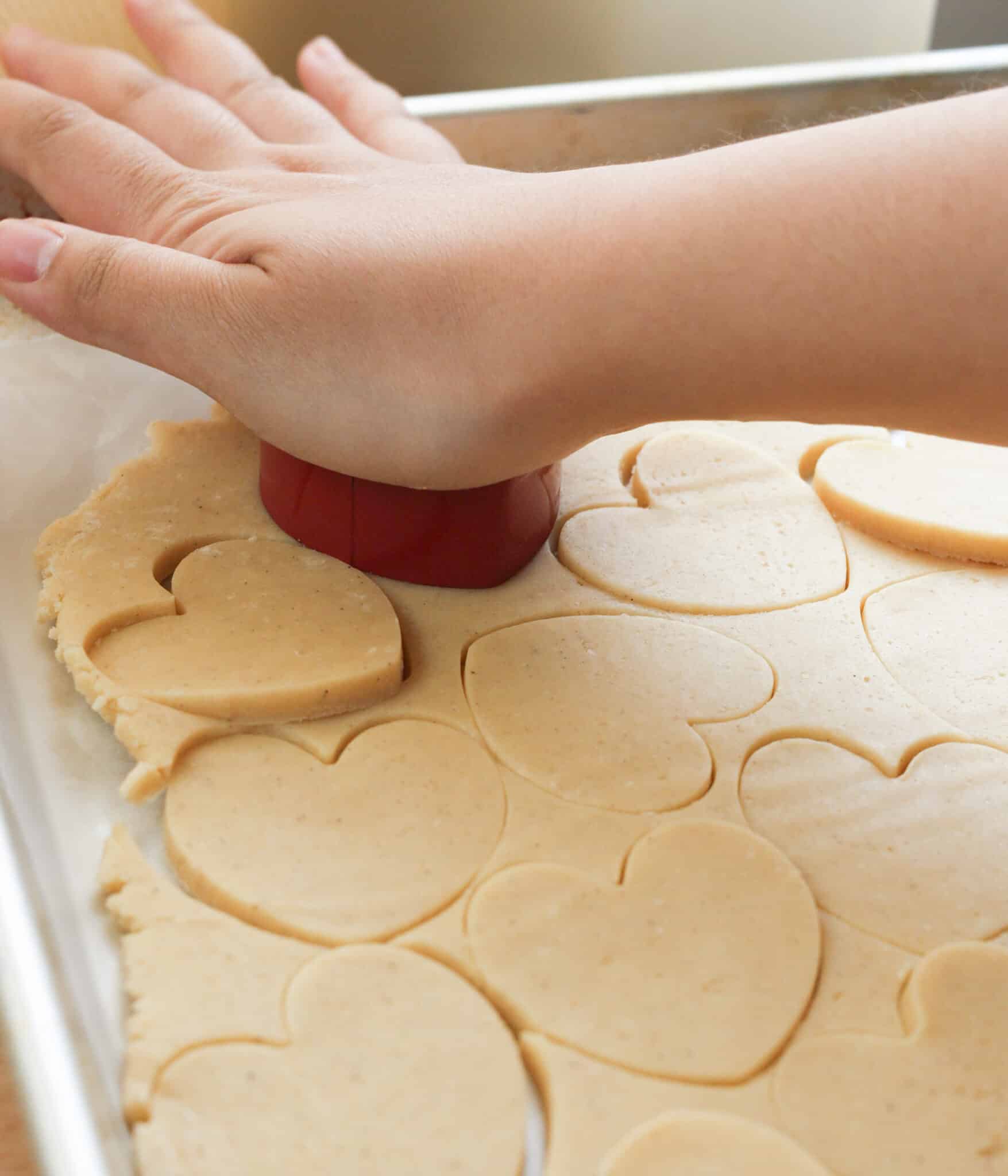 Using heart cookie cutters on sugar cookie dough.