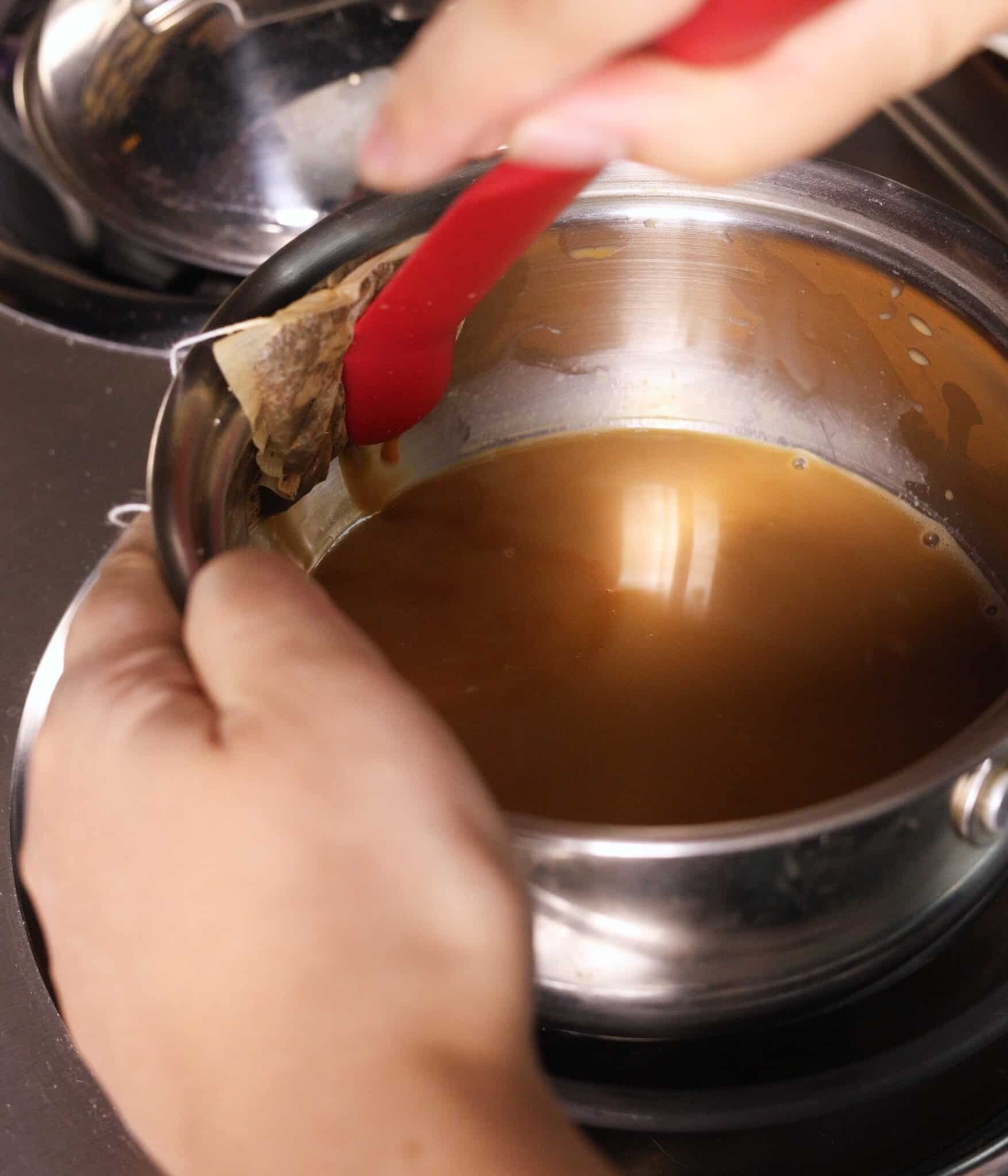 Squeezing out extra liquid from earl grey tea bag into pot.