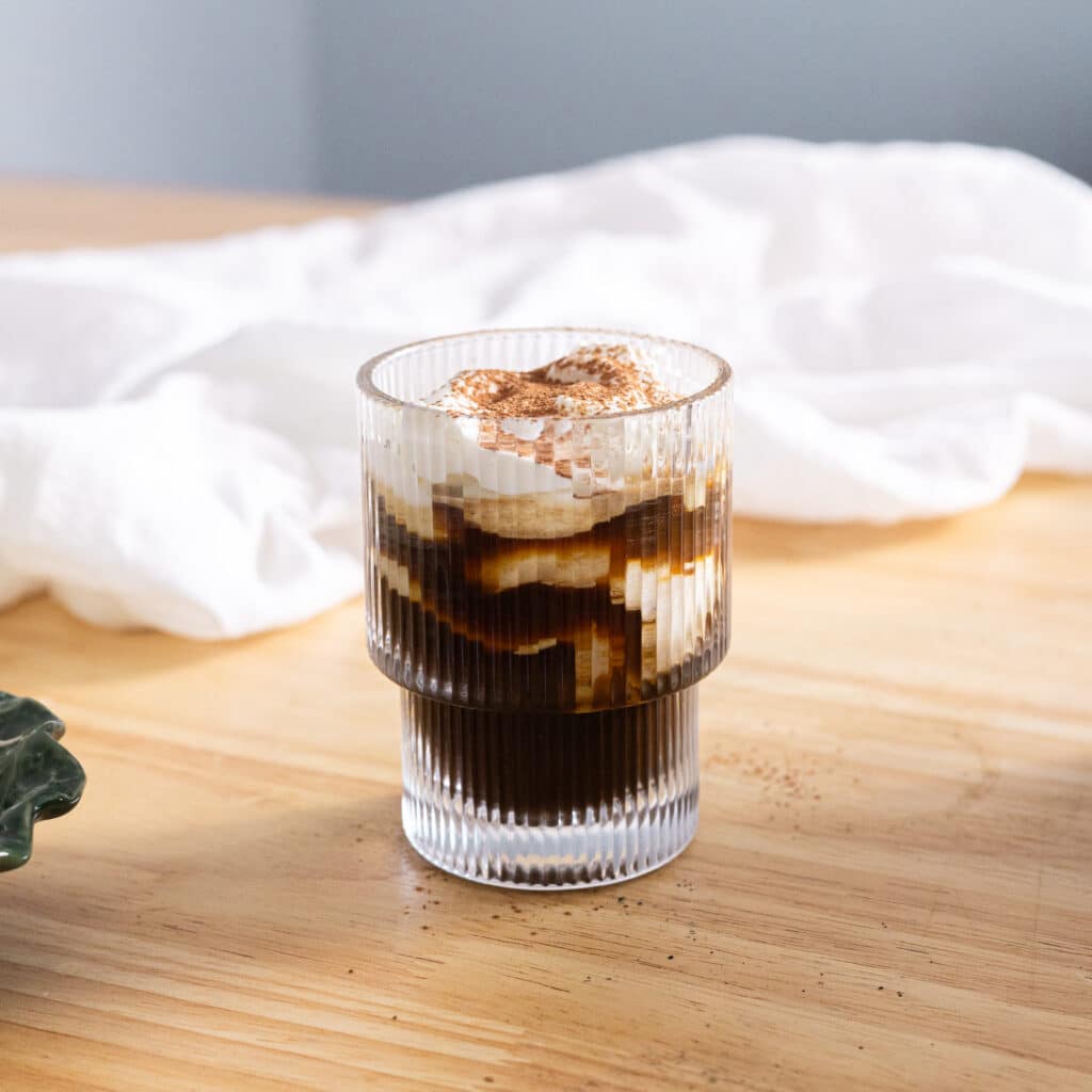 Einspanner topped with cocoa powder in a glass cup.