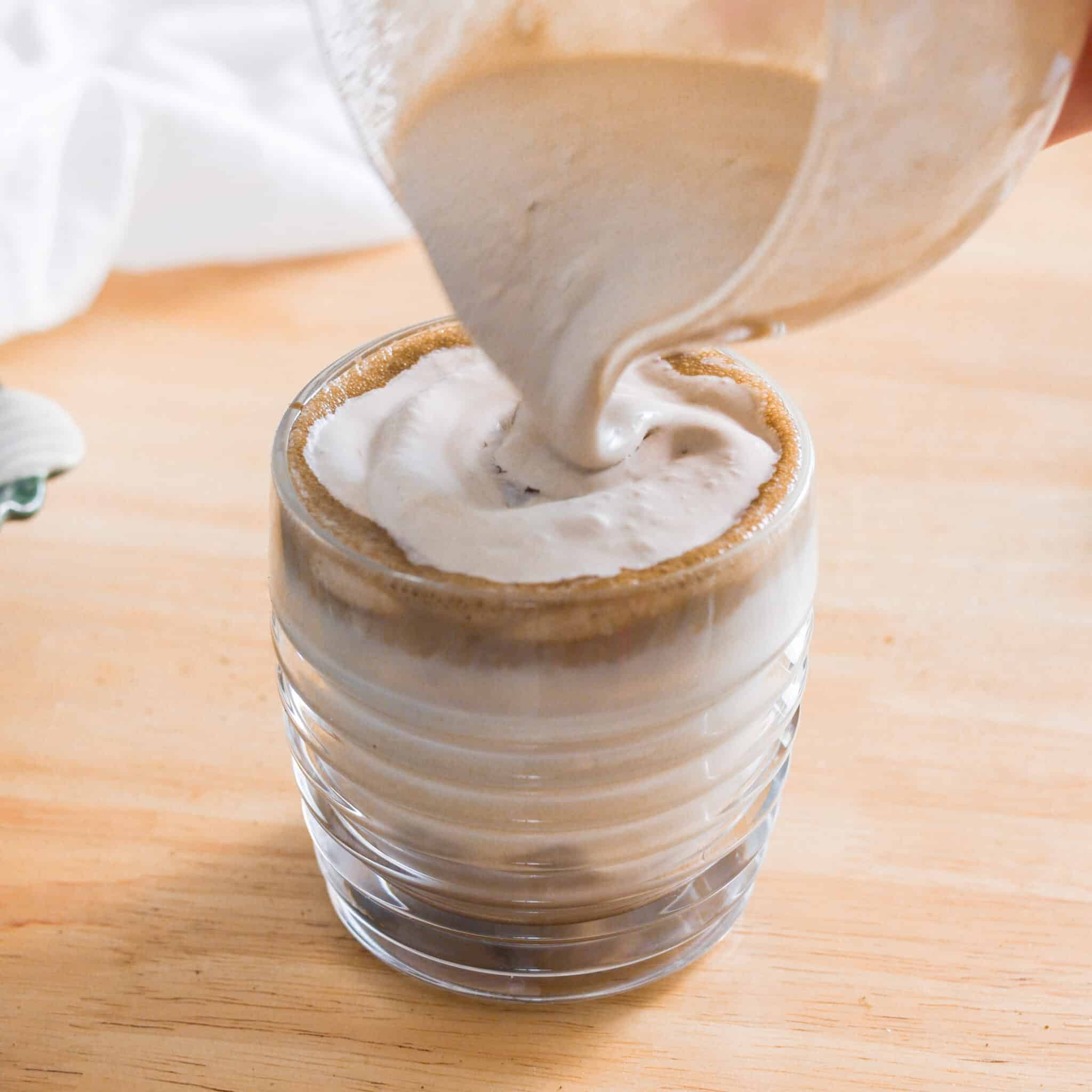 Pouring hojicha cold foam over hojicha latte.