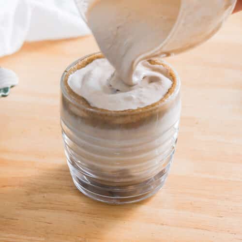 Pouring hojicha cold foam over hojicha latte.