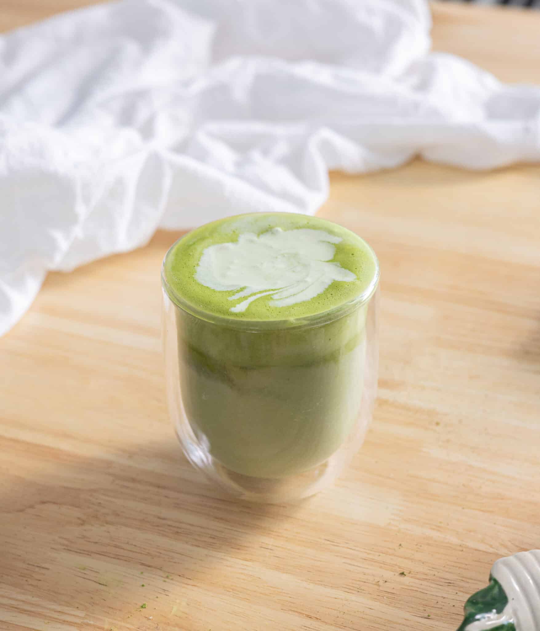 Matcha latte topped with matcha cold foam in a glass cup.