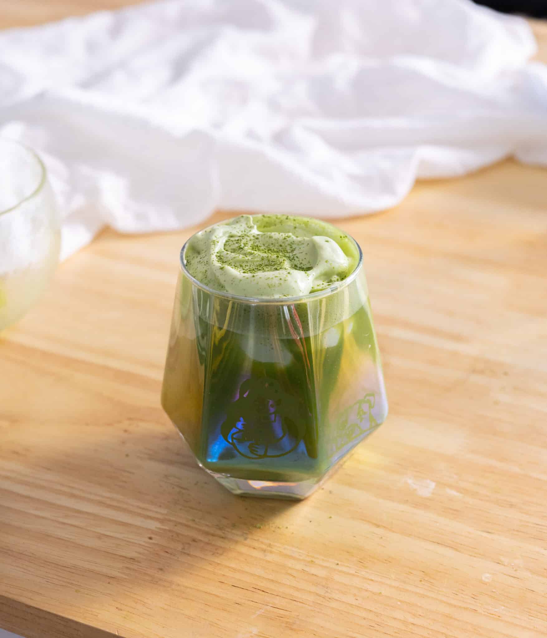 Matcha einspanner in a glass cup.