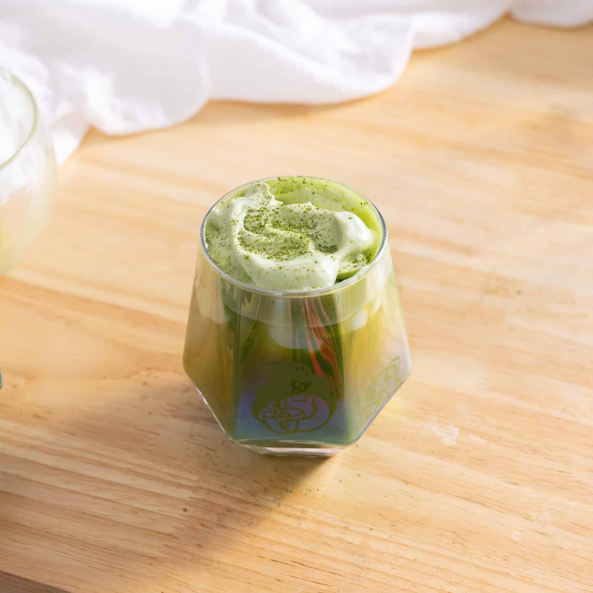 Matcha einspanner in a glass cup.
