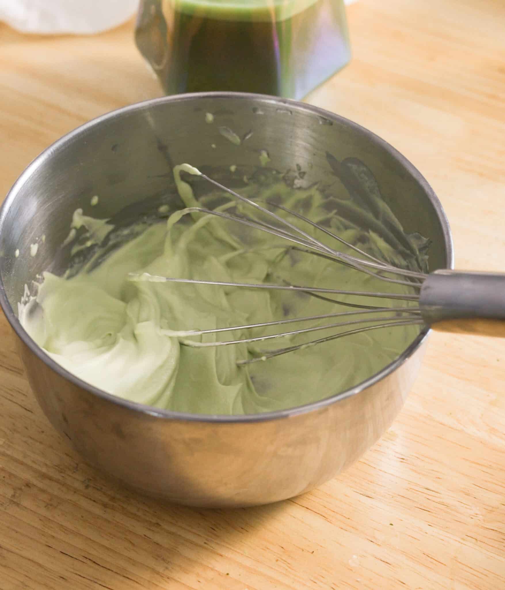 Homemade matcha whipped cream in a stainless steel bowl.