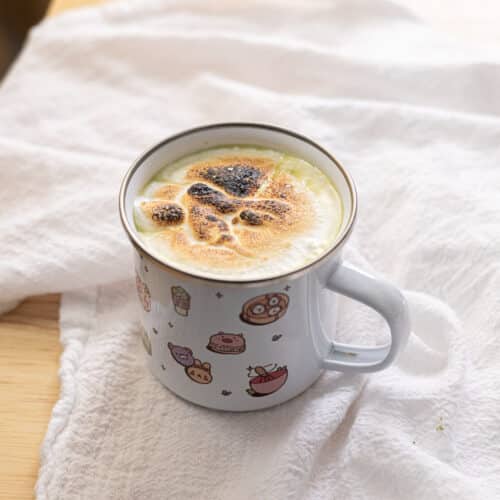 Matcha hot chocolate topped with torched marshmallow fluff in a mug.