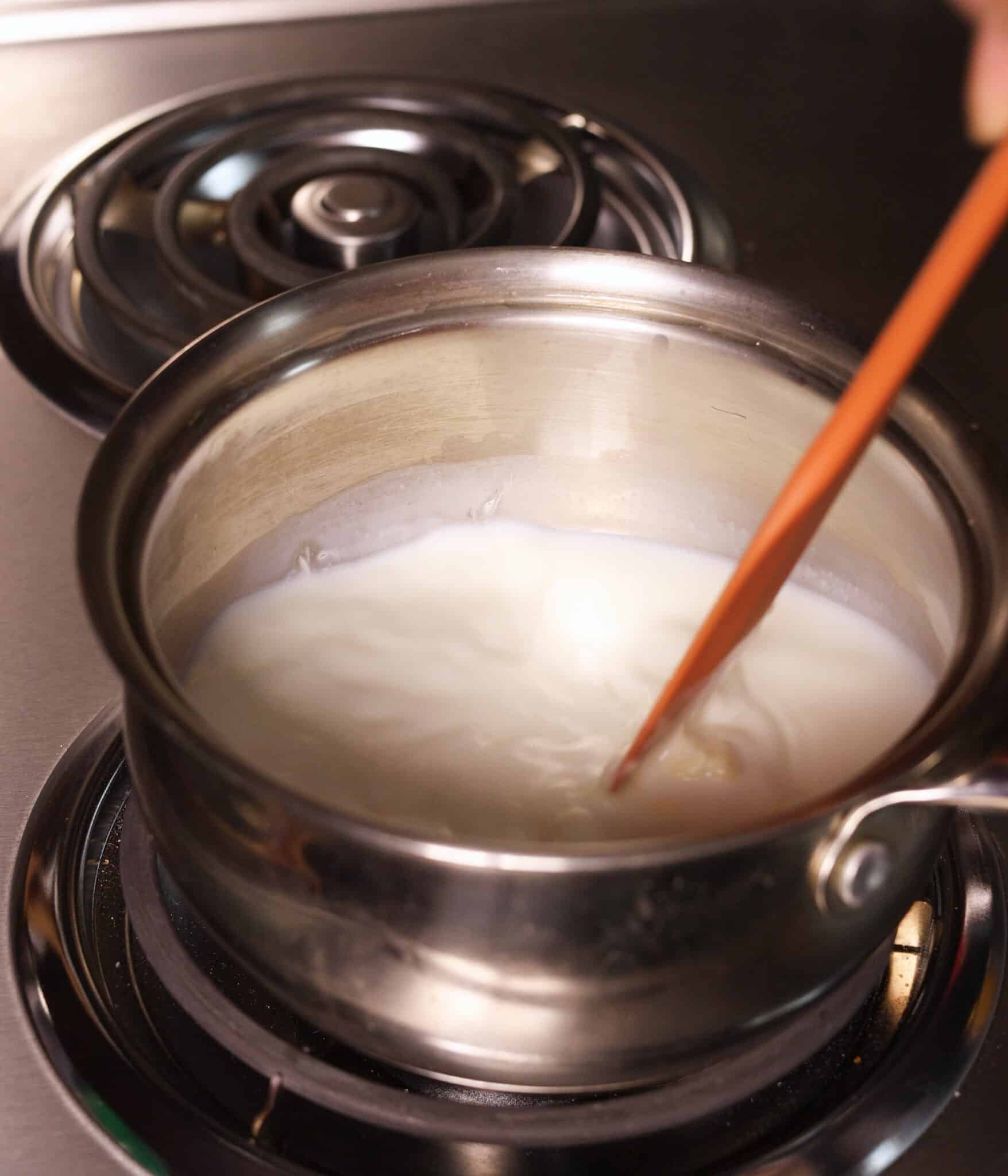 Mixing milk and white chocolate in a pot over medium heat.