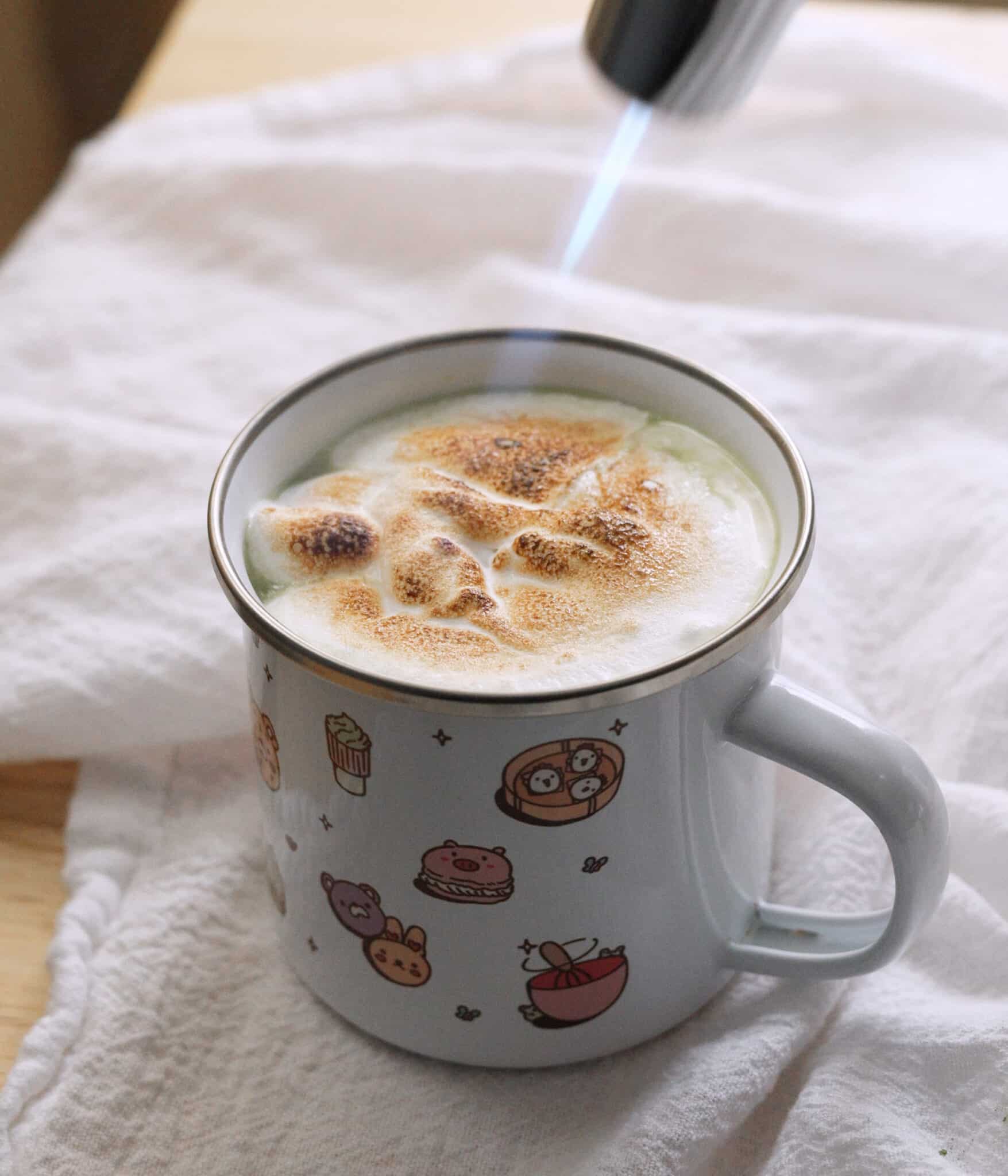 Blowtorching marshmallow fluff on top of matcha hot chocolate.