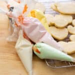 Royal icing in piping bags next to a tray of vanilla bean cut out cookies.