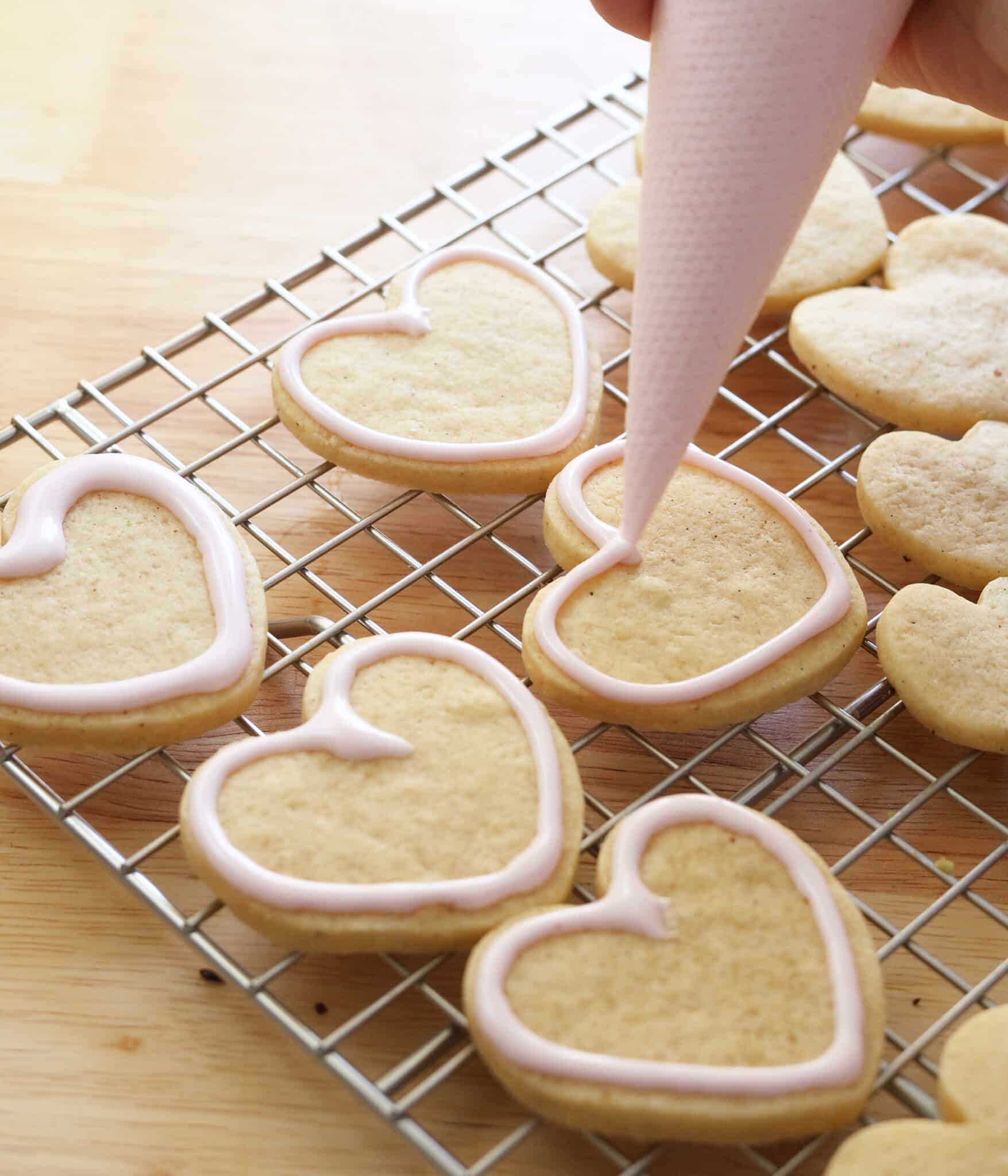 Piping royal icing border on cookies.