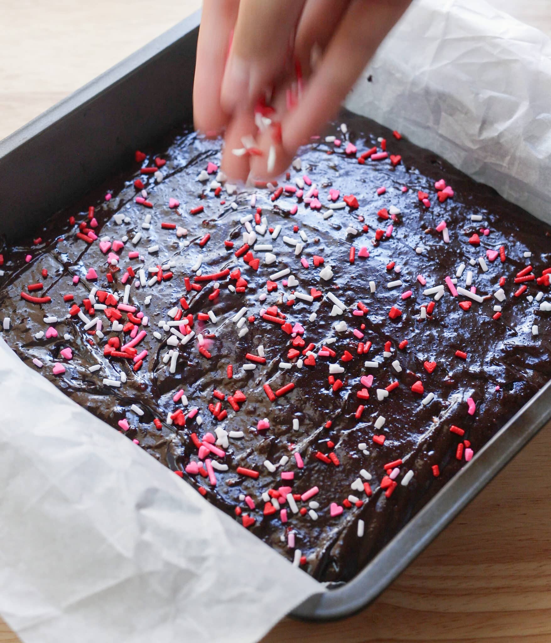 Topping brownie batter in pan with vday sprinkles right before baking.