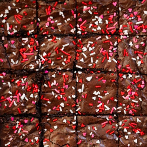 Valentine's Day brownies in a pan, topped with heart sprinkles.