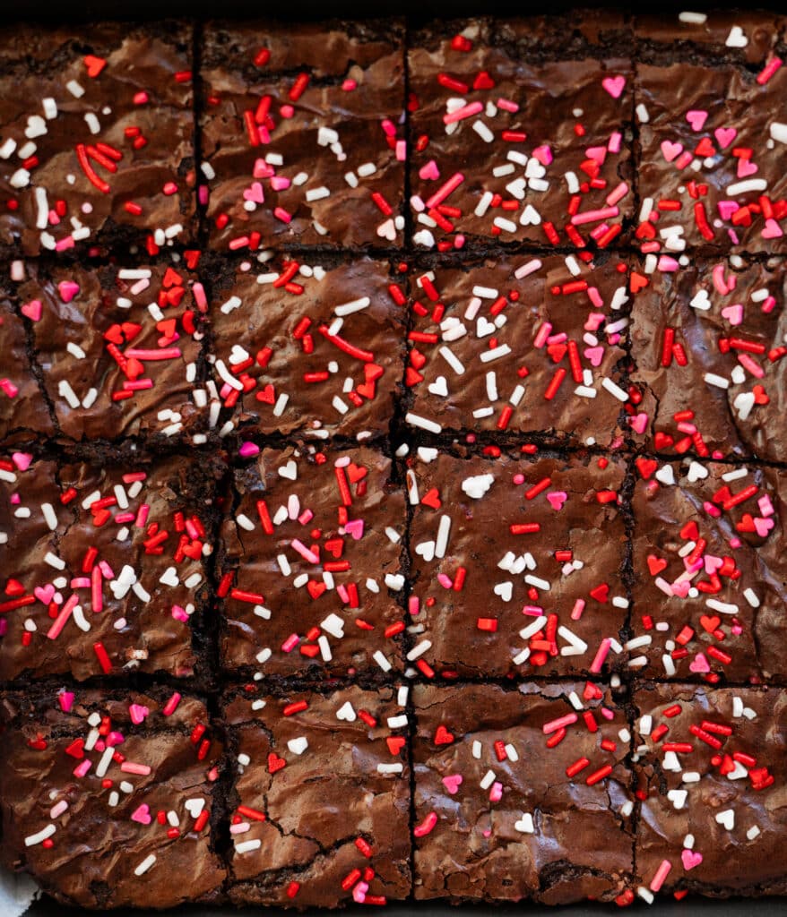 Valentine's Day brownies in a pan, topped with heart sprinkles.