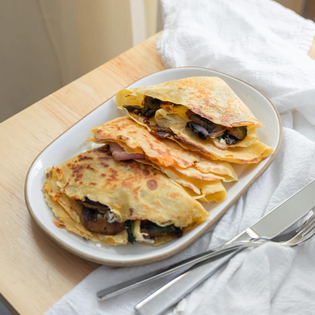 Two types of savory crepes on a plate.