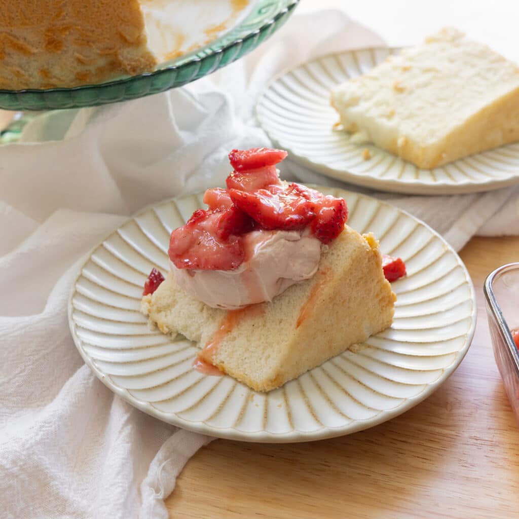 Pouring macerated strawberry juice on top of slice of angel food cake with whipped cream.