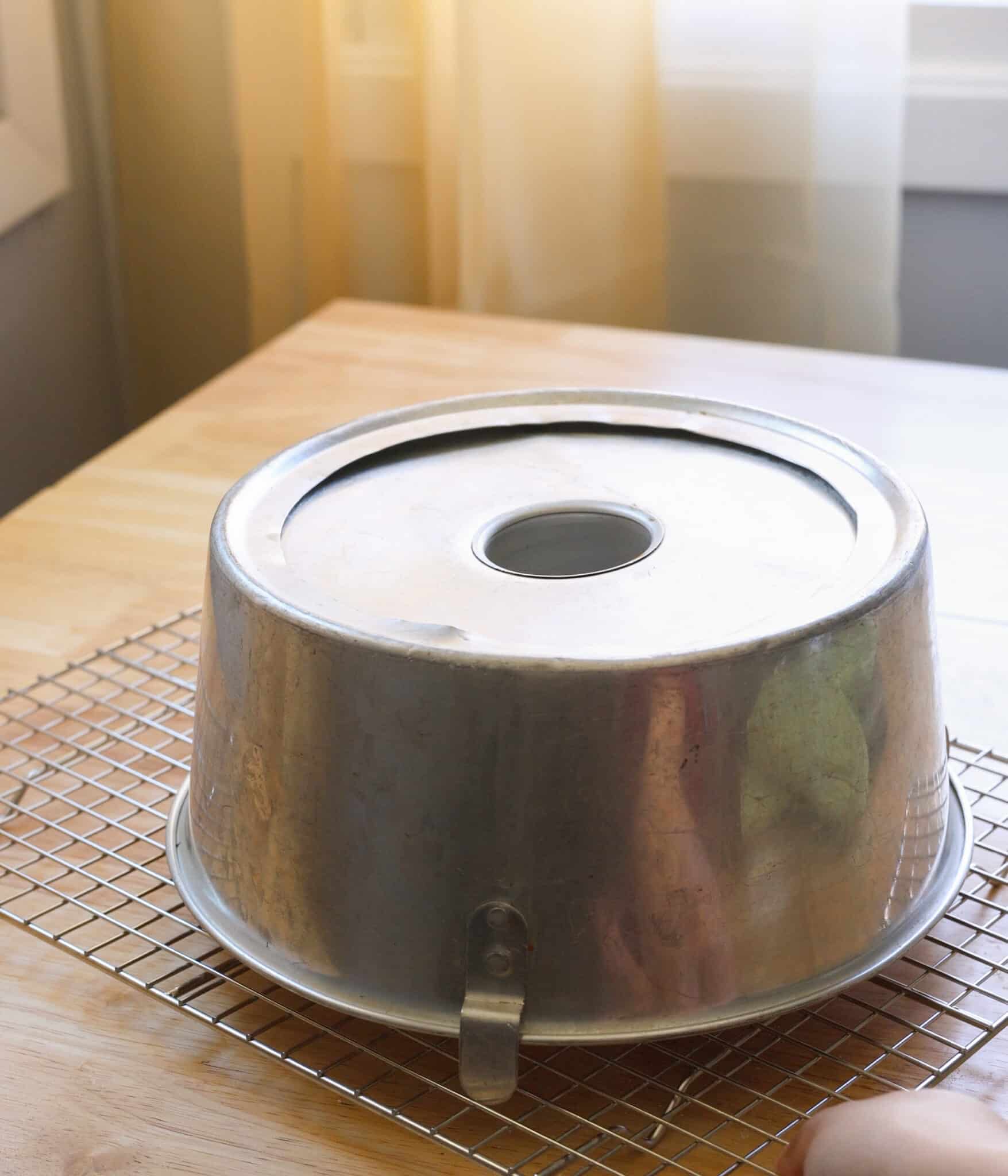 Cooling angel food cake upside down in pan.