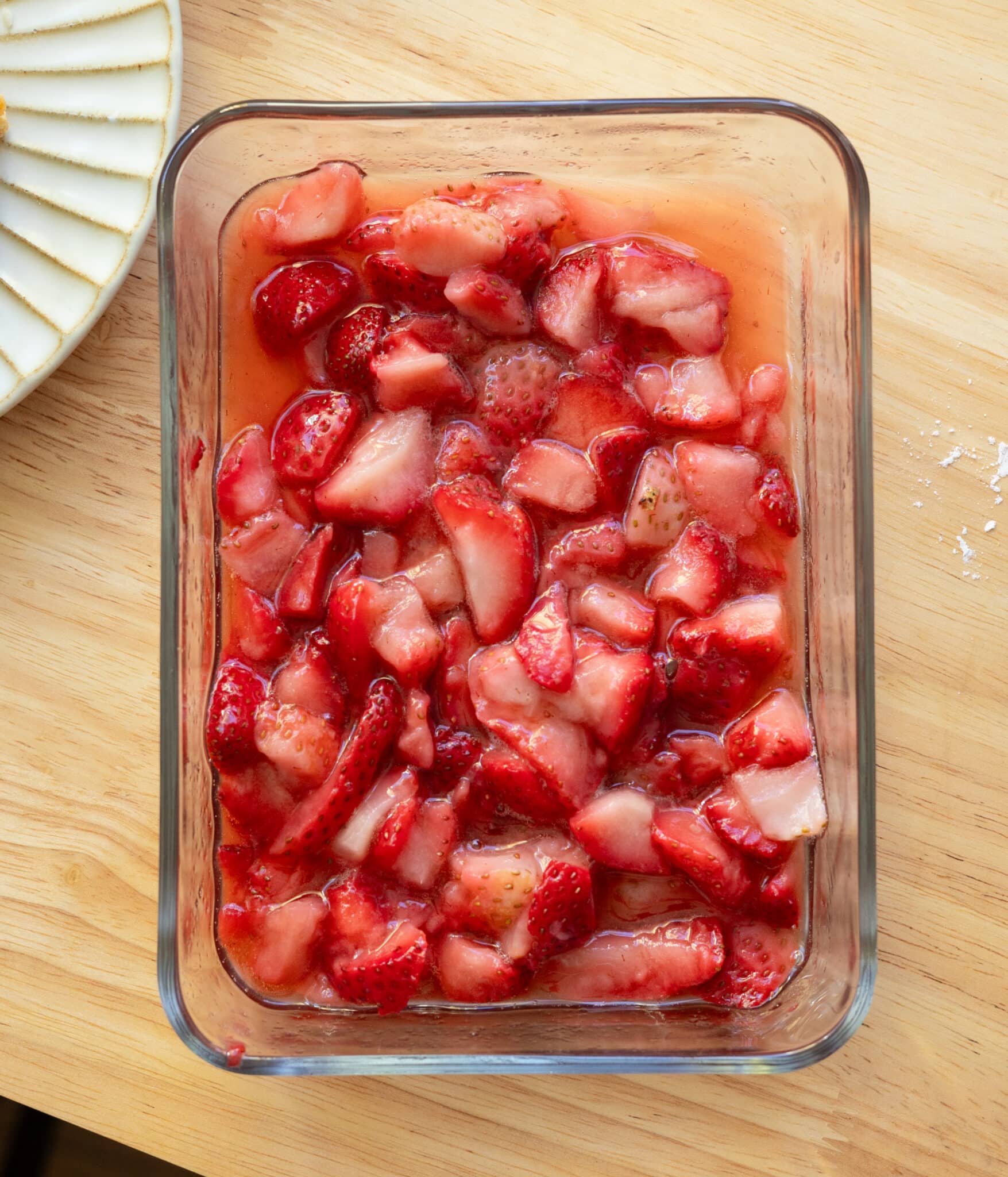 Macerated strawberries in a glass container.