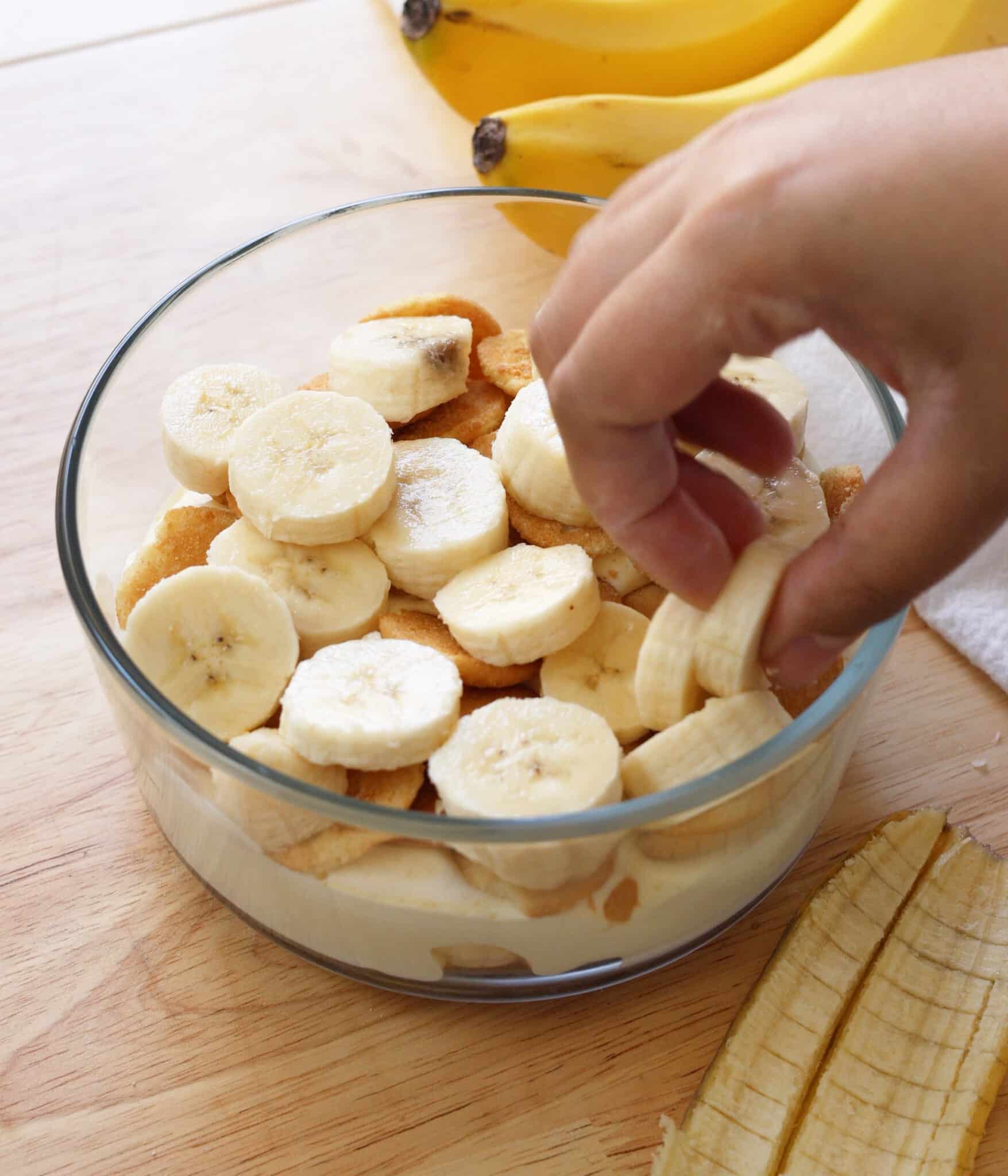 Layering sliced bananas on top of nilla wafers for banana pudding.