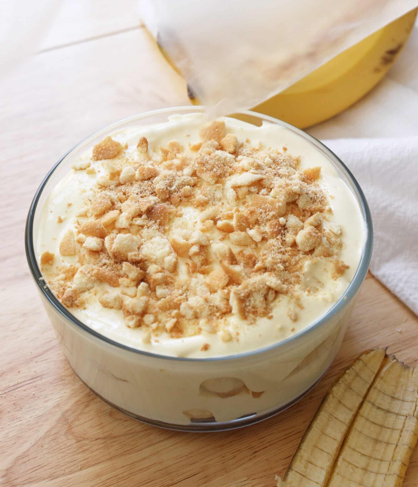 Sprinkling the top of the banana pudding with crushed vanilla cookies.