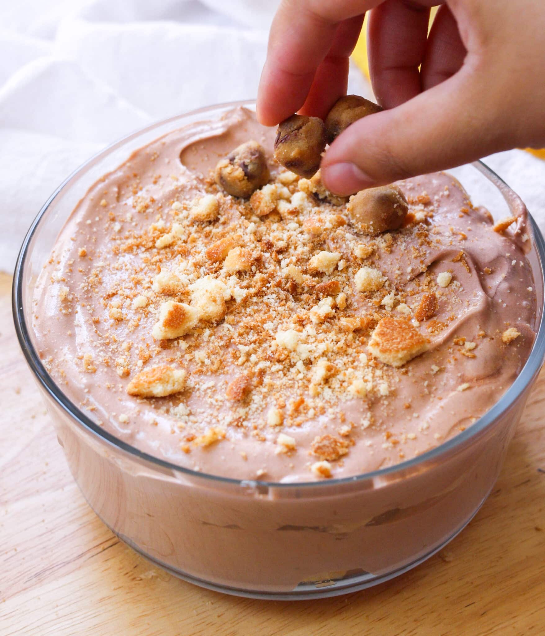 Adding cookie dough on top of chocolate banana pudding.