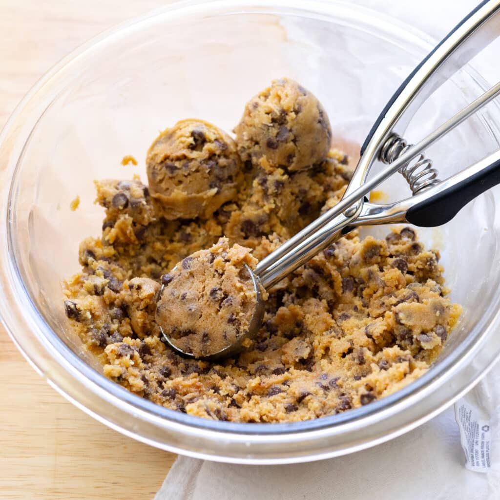 Scoopable edible cookie dough in a glass mixing bowl.