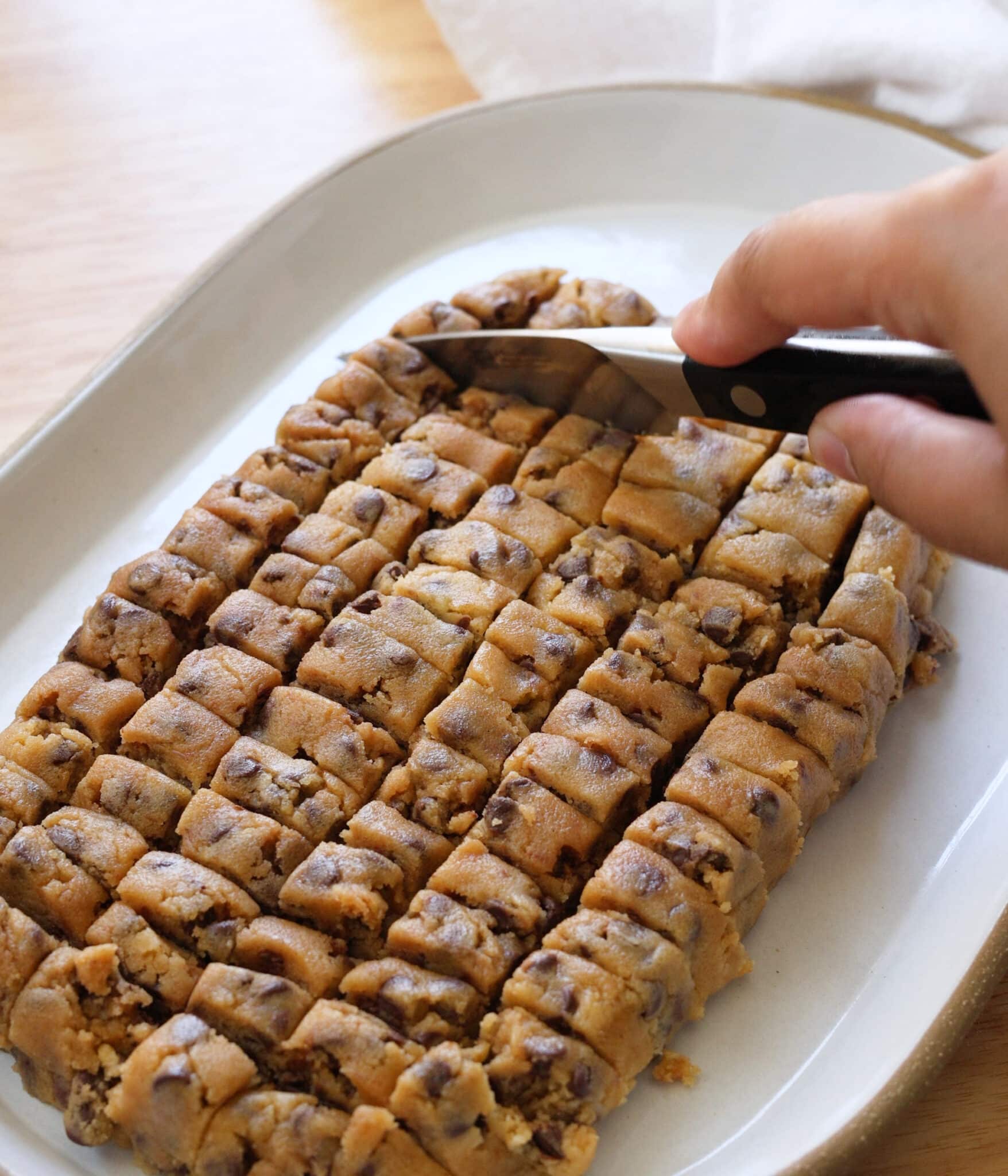 Evenly cutting cookie dough to roll out cookie dough bites.
