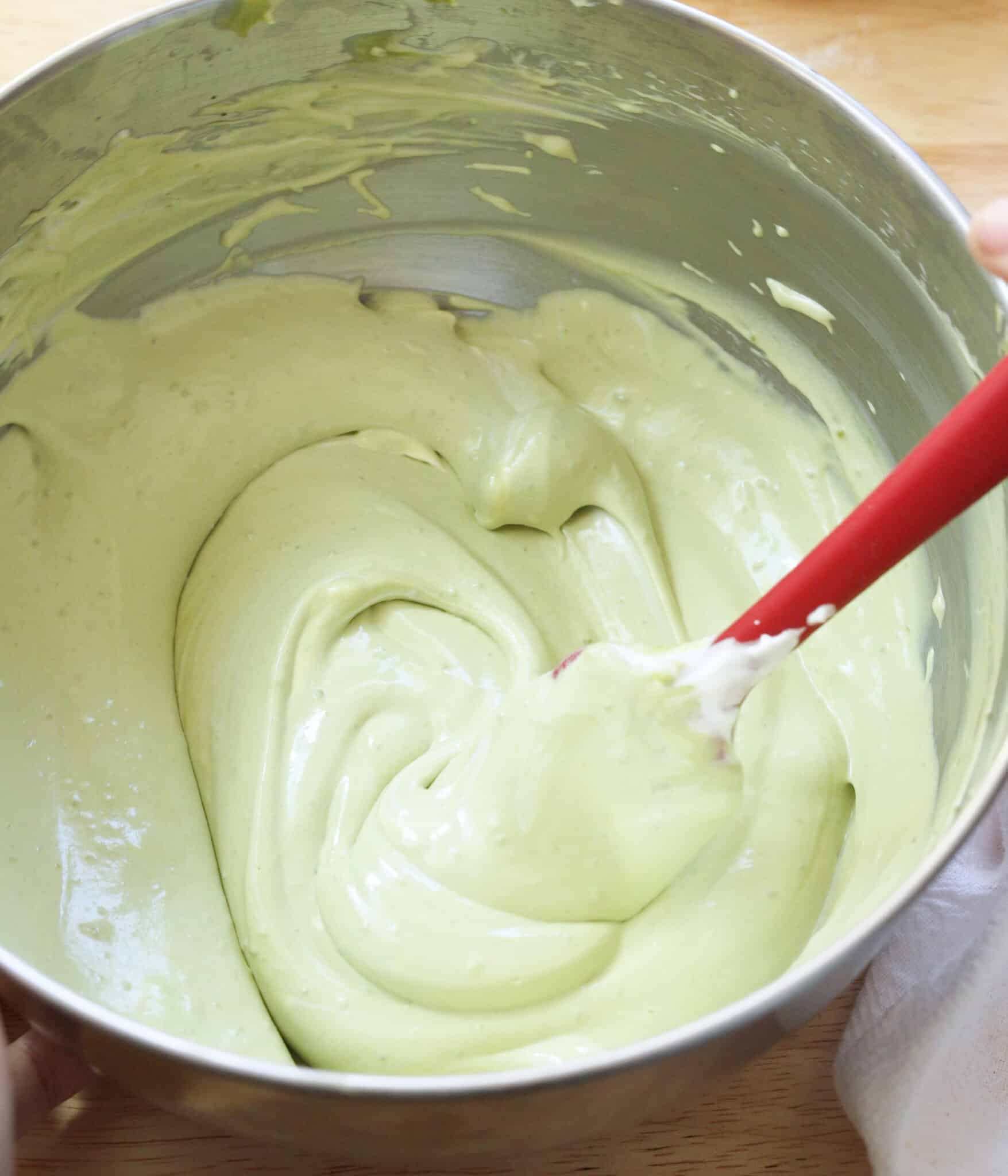 Light and creamy matcha pudding mixture in a stainless steel bowl.